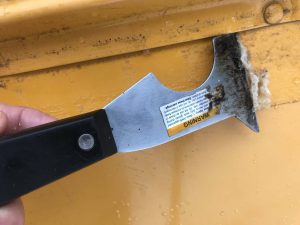Using a paint scraper to remove adhesive from skoolie